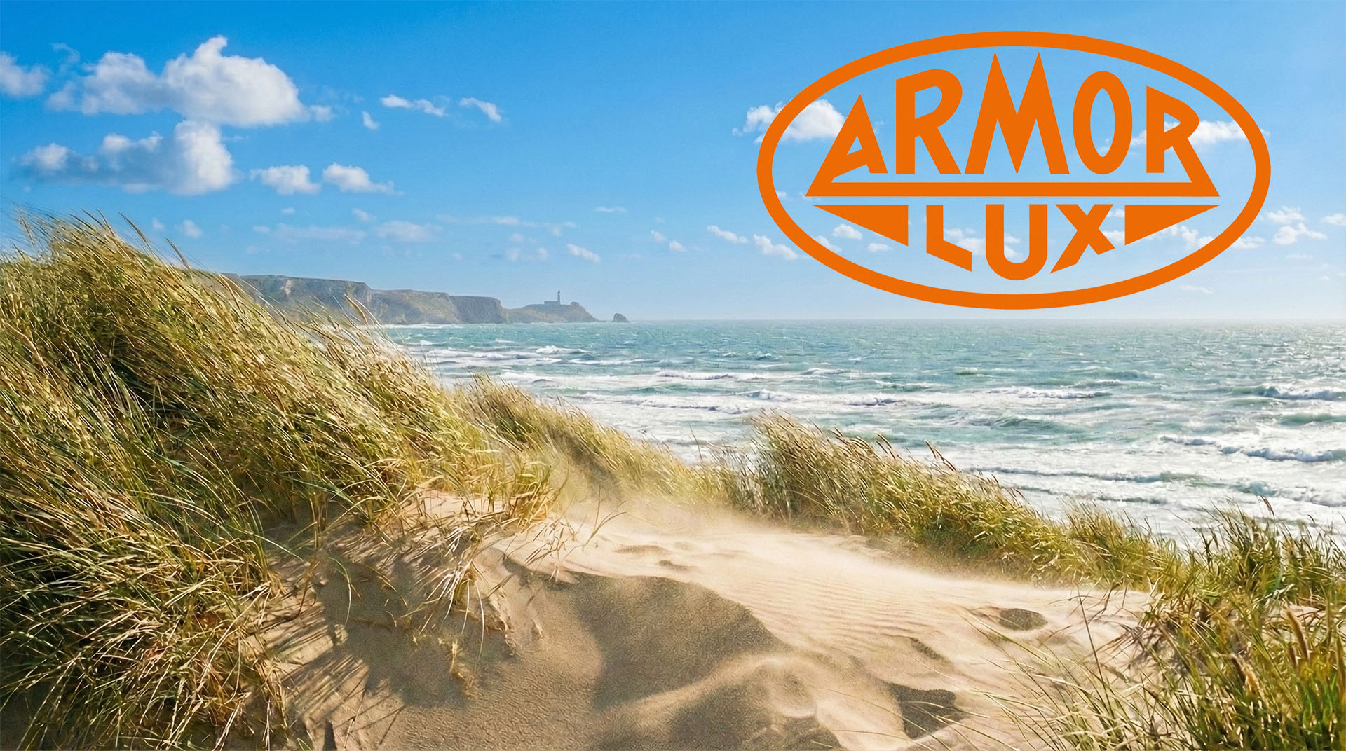 Küstenlandschaft mit Dünen und Strandgras, vom Wind verwehter Sand, Wellen im Hintergrund und orangefarbenes ARMOR LUX Logo im Himmel.